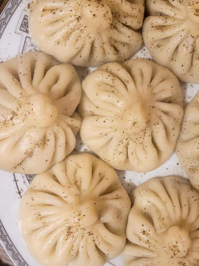 Souple dumplings on a white plate with cracked black pepper