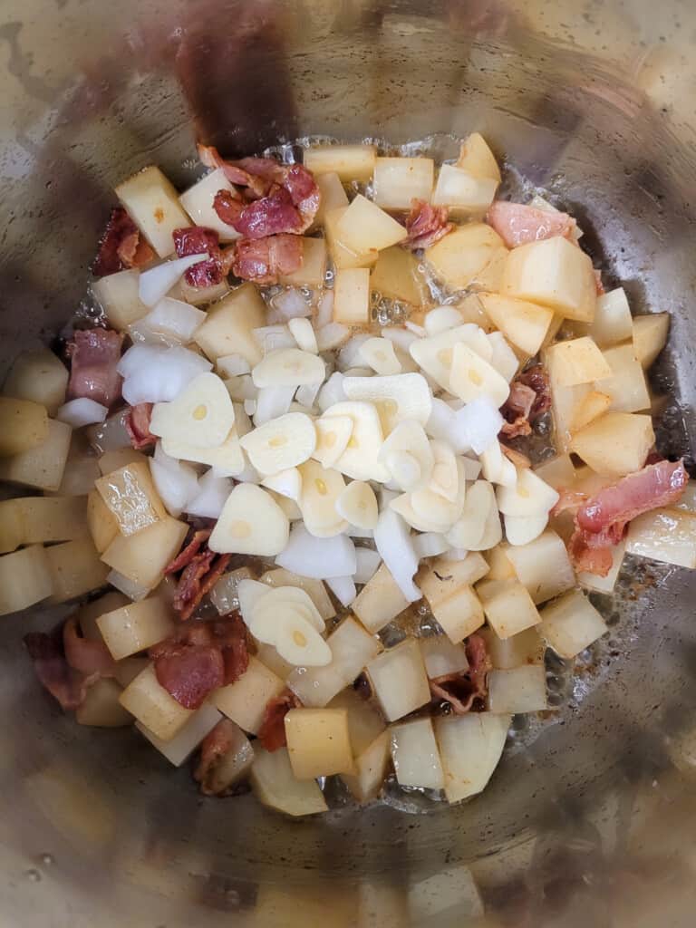 Garlic, onions, bacon, and potatoes in a silver pot