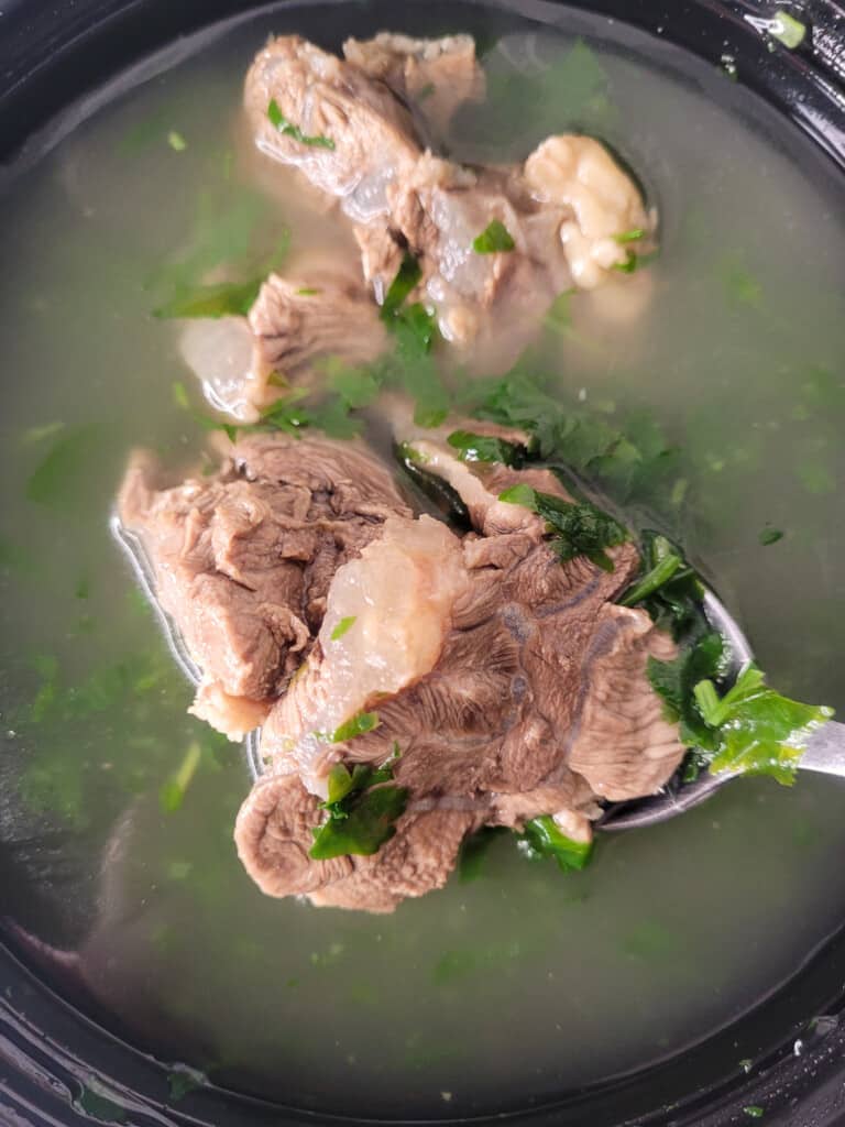 Closeup of tatariakhni beef bone broth soup in a black bowl