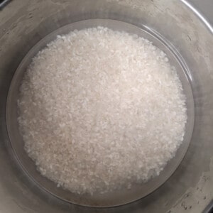 Raw white rice submerged in water in a pot