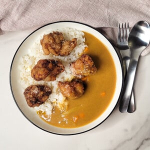 Overhead view of a plate with rice, Japanese curry, and chicken karaage next to utensils