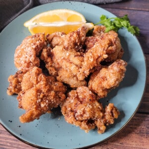 A blue plate with Japanese fried chicken or chicken karaage next to lemon wedges