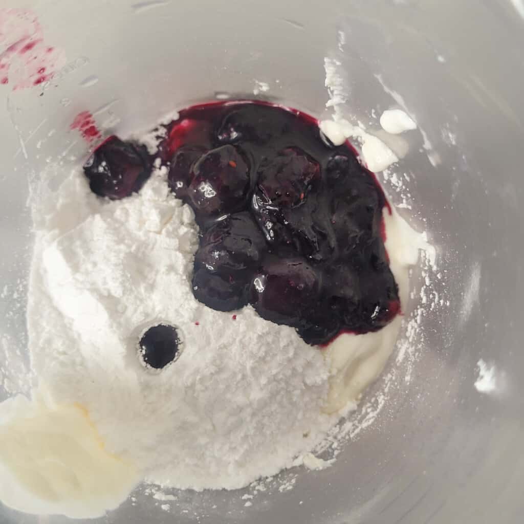 Blueberry sauce in a bowl with whippe cream ingredients