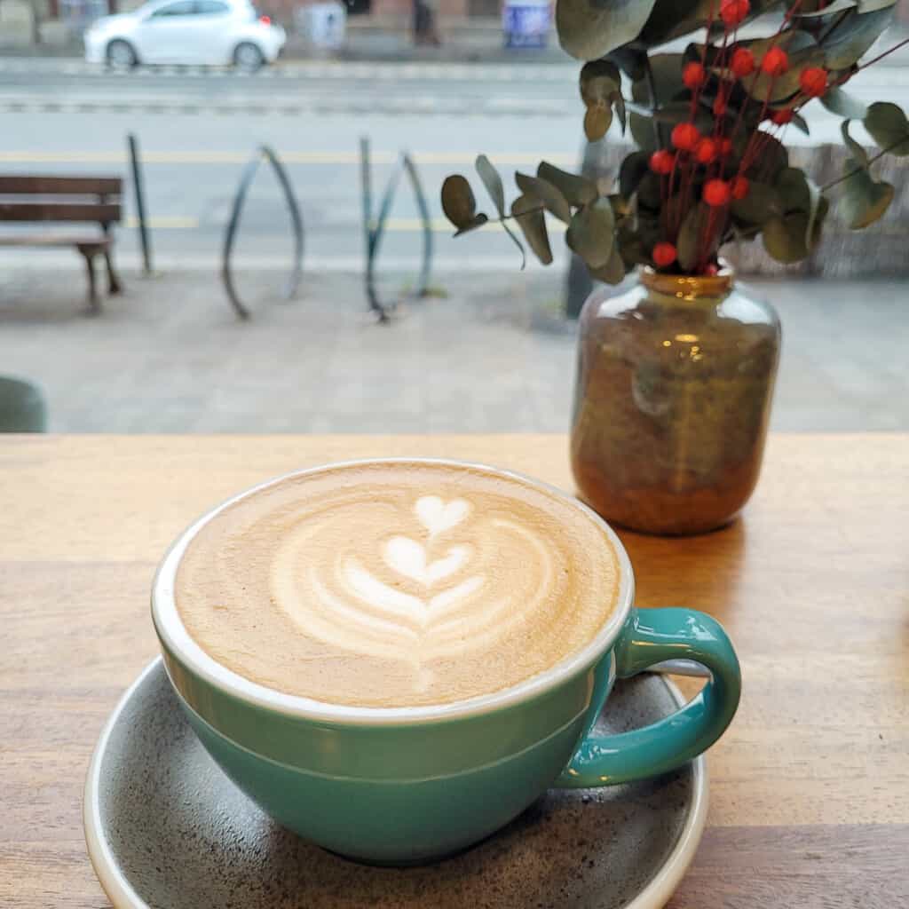 Flat white in a teal mug on a wooden table at a cafe in Budapest