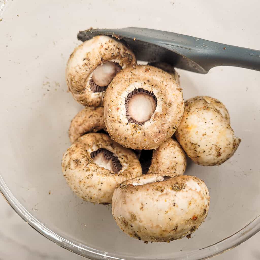 Seasoned mushrooms in a bowl with a spatula
