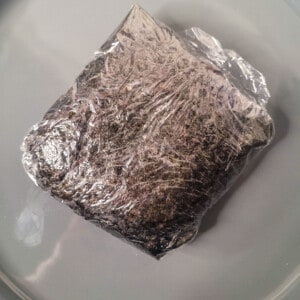 A square sandwich covered with seaweed on a plate