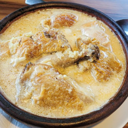 Chkmeruli with white garlic sauce in a clay pan