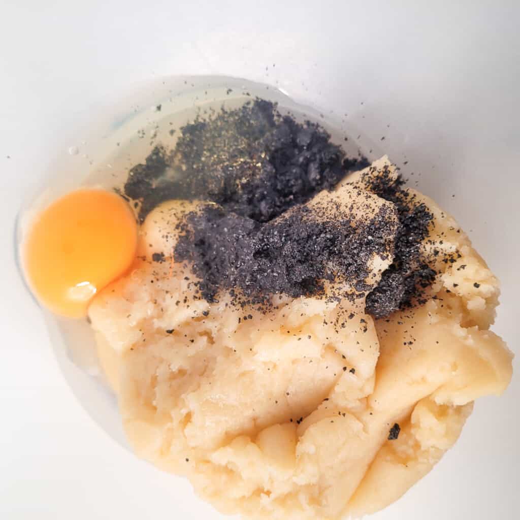 Cooked churro dough, egg, and ground black sesame seeds in a bowl