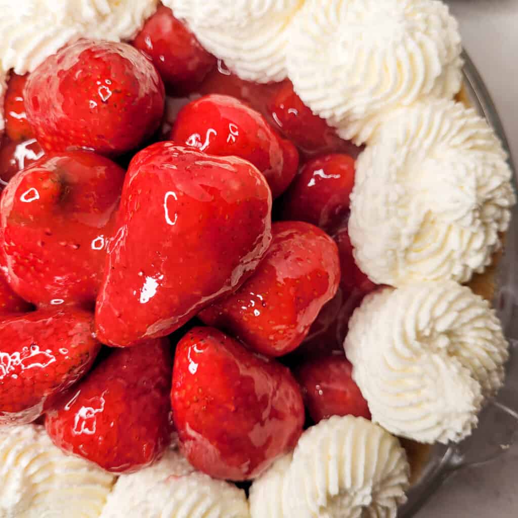 Closeup of a strawberry on strawberry custard pie.