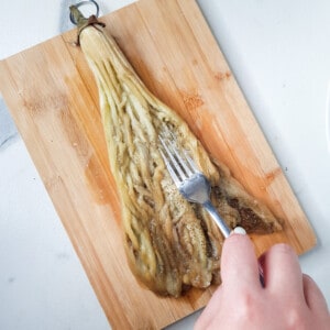 Flattened eggplant with fork on a cutting board