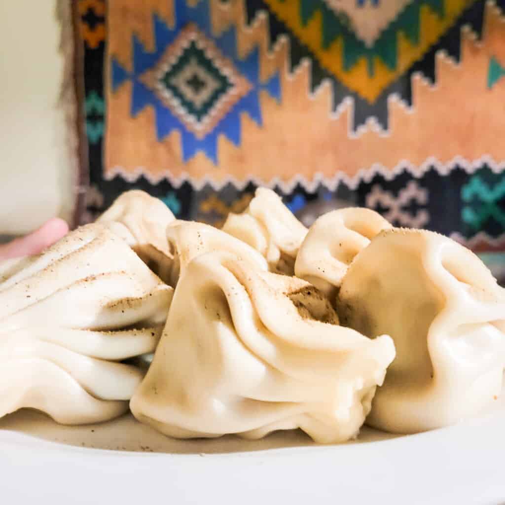 A plate of khinkali in front of a Georgian tapestry