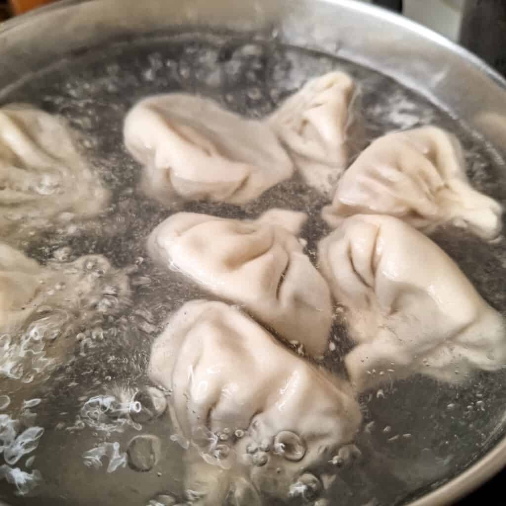 Meat khinkali (Georgian dumplings) in boiling water.