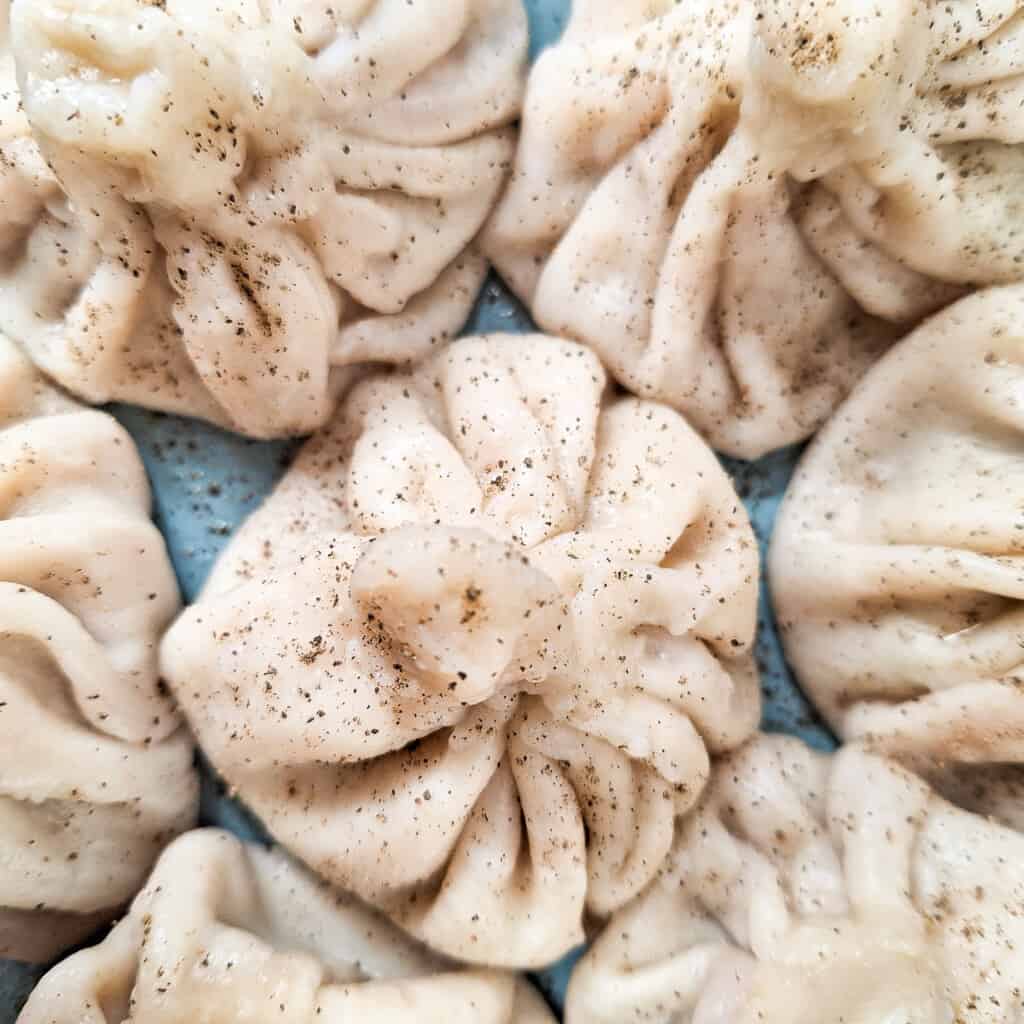 Closeup of meat dumplings with pepper on top of them.