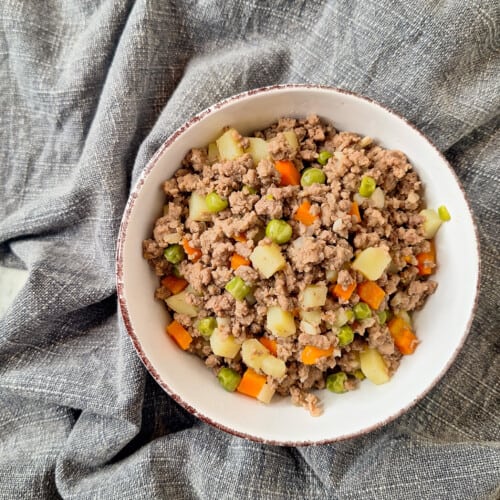 Beef and pork giniling in a white bowl on top of a blue towel