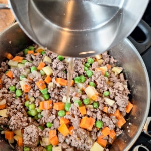 Pouring water into a pot of minced meat and diced vegetables