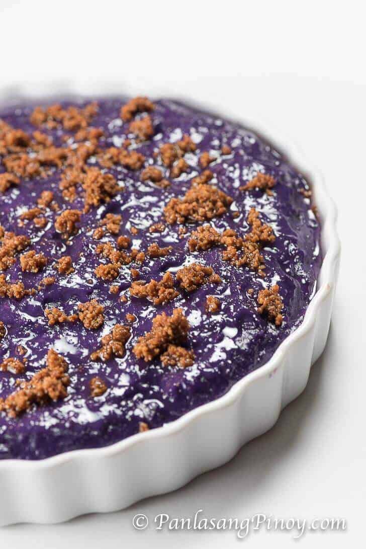 Ube kalamay or ube sticky dessert in a white bowl topped with coconut curds