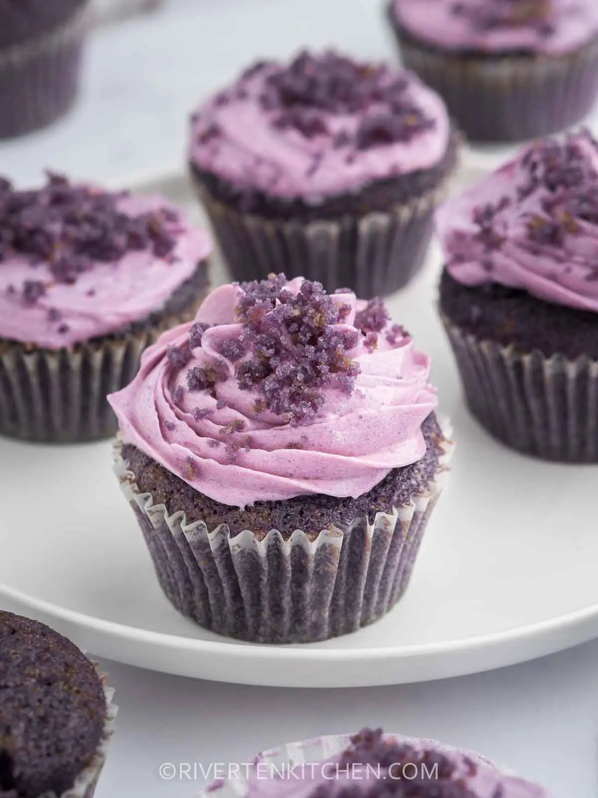 Multiple ube cupcakes arranged in a line on a white tray