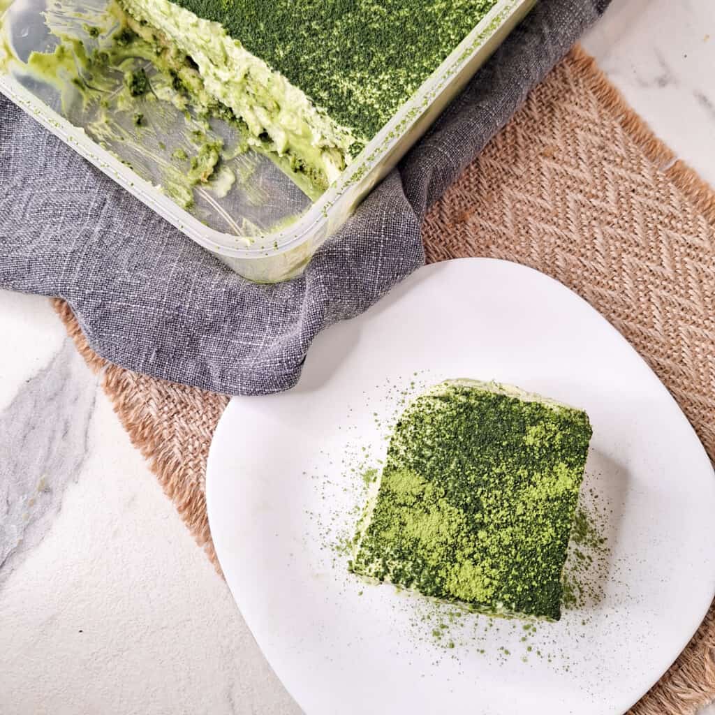 A slice of matcha tiramisu next to a container