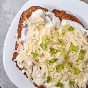 A langos or Hungarian deep fried bread with a topping of sour cream, cheese, and green onions