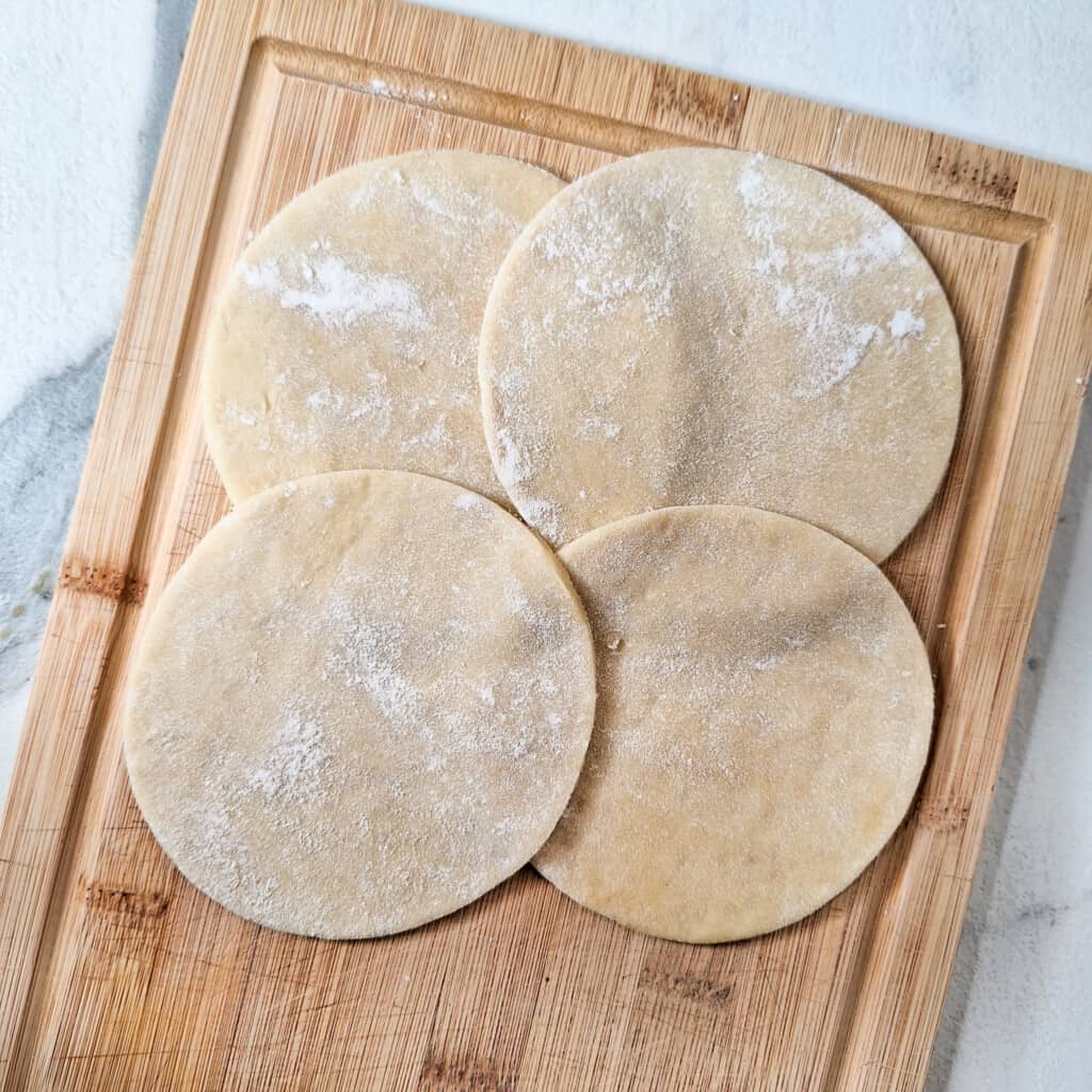 Empanada dough pieces on a wooden board