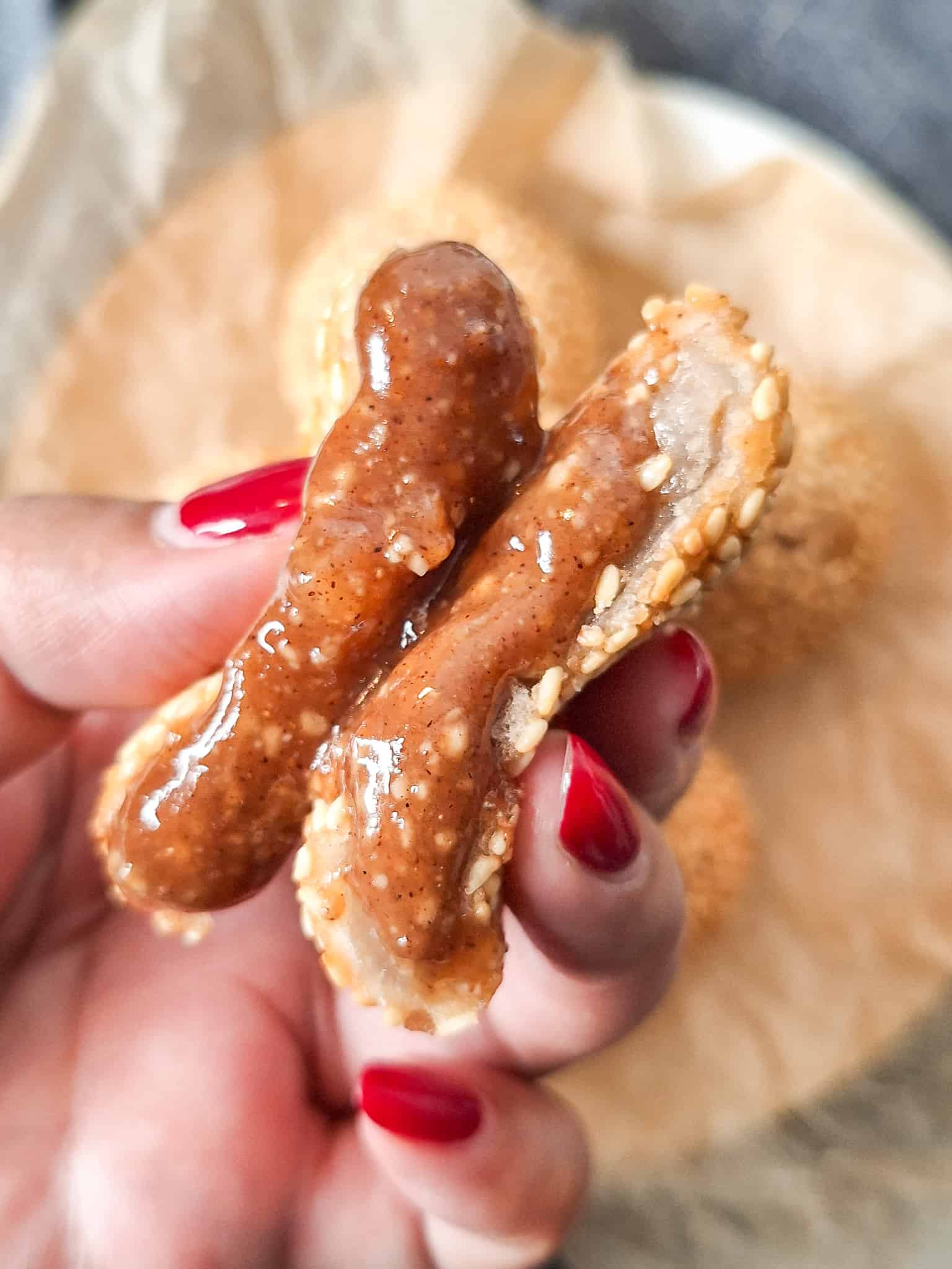 Hand squeezing the filling out of fried sesame balls