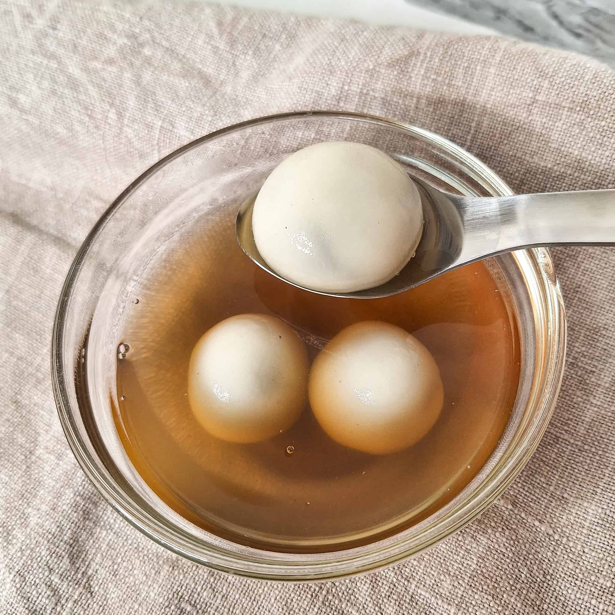 Spoon holding a piece of tang yuan over a bowl