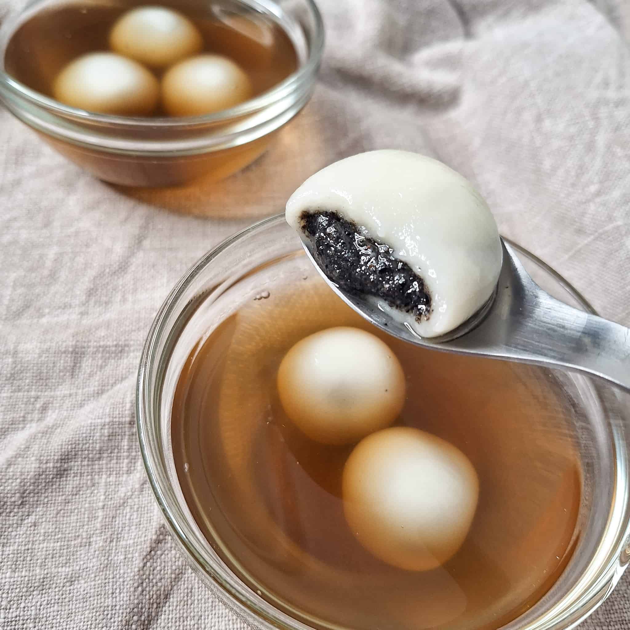 Cross-section of black sesame paste above a bowl of tang yuan in ginger tea