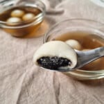 Close up of cross-section of black sesame paste above a bowl of tang yuan in ginger tea