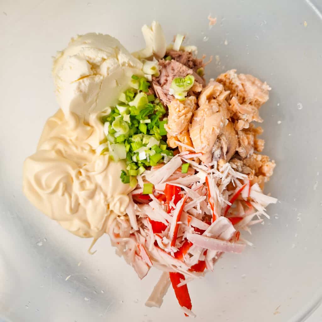 Canned tuna, canned salmon, chopped green onions, cream cheese, imitation crab, and Kewpie mayo in a plastic bowl